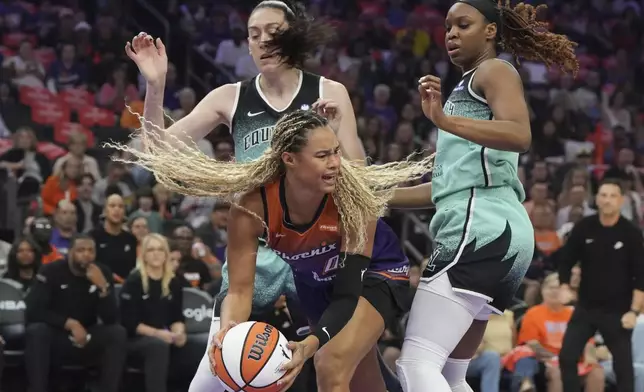 Phoenix Mercury forward Satou Sabally, center, tries to pass between New York Liberty forward Breanna Stewart, left, and forward Kennedy Burke during the first half of Game 3 in the first round of the WNBA basketball playoffs, Friday, Sept. 19, 2025, in Phoenix. (AP Photo/Rick Scuteri)
