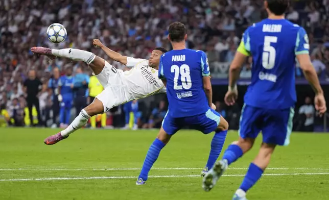 Real Madrid's Kylian Mbappe, left, shoots a high ball next to Marseille defenders during a Champions League opening phase soccer match between Real Madrid and Marseille at Santiago Bernabeu stadium, in Madrid, Tuesday, Sept. 16, 2025. (AP Photo/Manu Fernandez)
