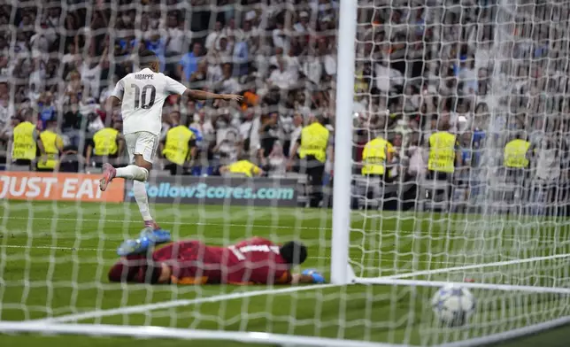 Real Madrid's Kylian Mbappe, top, celebrates after scoring past Marseille's goalkeeper Geronimo Rulli his side's second goal during a Champions League opening phase soccer match between Real Madrid and Marseille at Santiago Bernabeu stadium, in Madrid, Tuesday, Sept. 16, 2025. (AP Photo/Manu Fernandez)