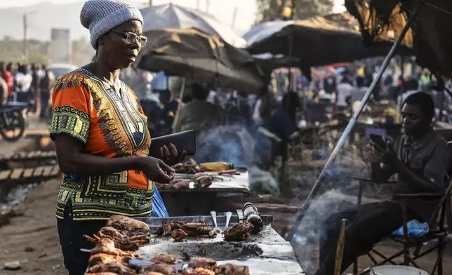 A woman buys food from a street vendor in Zomba, Malawi, Wednesday, Sept. 10, 2025. (AP Photo/Thoko Chikondi)
