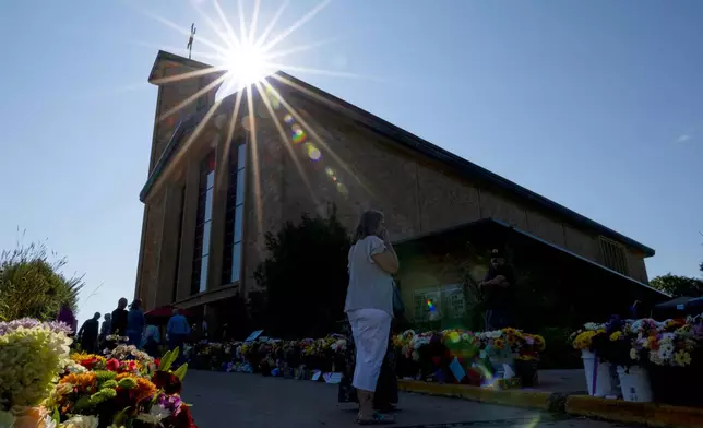 The sun shines over the memorial outside Annunciation Catholic Church during Mass after Wednesday's shooting, Sunday, Aug. 31, 2025, in Minneapolis.(AP Photo/Ellen Schmidt)