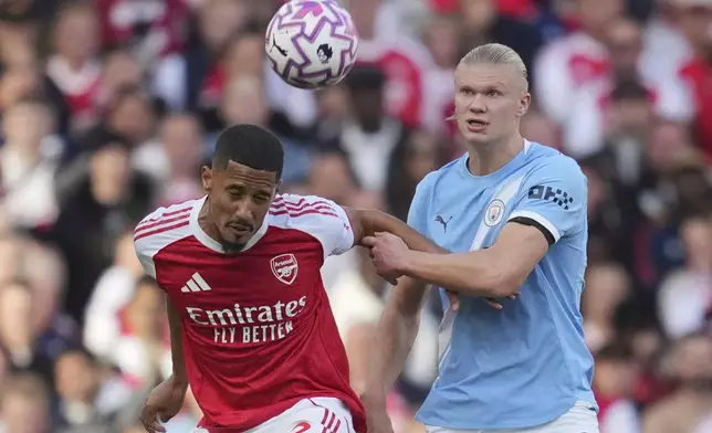 Arsenal's William Saliba, left, and Manchester City's Erling Haaland fight for the ball during the Premier League soccer match between Arsenal and Manchester City in London, Sunday, Sept. 21, 2025. (AP Photo/Kin Cheung)