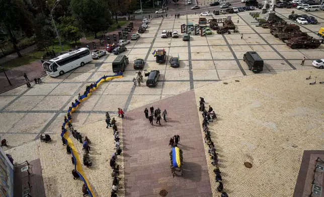 People kneel down, as honor guards carry the coffin of Artem Antonenko, a Ukrainian serviceman, during his funeral ceremony in the center of Kyiv, Ukraine, Friday, Sept. 19, 2025. (AP Photo/Evgeniy Maloletka)