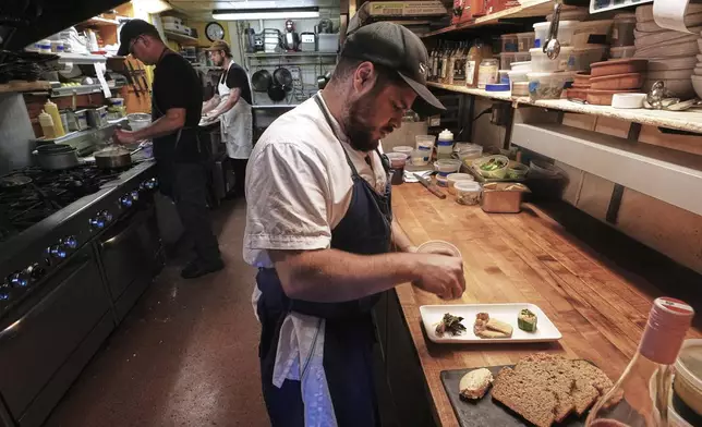 Chef Jake Vatalaro sprinkles locally foraged locust flower seasoning on a Chef's Meze Plate, which includes locally foraged mushrooms, at the Black Trumpet restaurant, Tuesday, Sept. 16, 2025, in Portsmouth, N.H. (AP Photo/Charles Krupa)