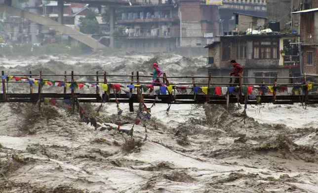FILE - Residents run across a bridge over the flooding Beas River following incessant rains in Kullu, in northern Indian state of Himachal Pradesh, Aug. 26, 2025. (AP Photo/Aqil Khan, File)