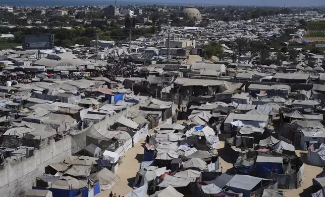 Displaced Palestinians walks through a tent camp in Muwasi, an area that Israel has designated as a safe zone, in Khan Younis southern Gaza Strip, Wednesday, Sept. 10, 2025. (AP Photo/Jehad Alshrafi)