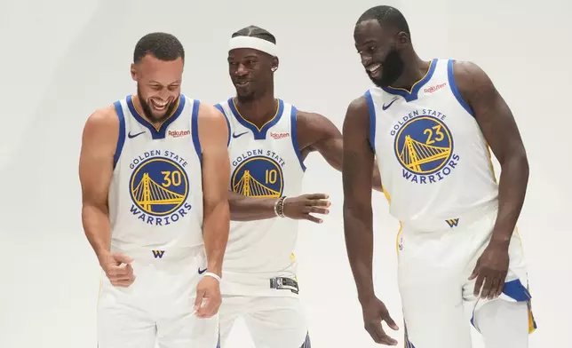 Golden State Warriors guard Stephen Curry, left, smiles while posing for photos with forward Jimmy Butler III, middle, and forward Draymond Green during the NBA basketball team's media day in San Francisco, Monday, Sept. 29, 2025. (AP Photo/Jeff Chiu)