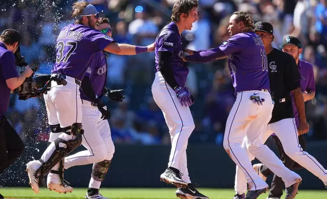 Colorado Rockies' Mickey Moniak, center, celebrates after his walkoff RBI single with Braxton Fulford (37) and Tyler Freeman, back left, and Orlando Arcia, front right, in the ninth inning of a baseball game against the Chicago Cubs, Sunday, Aug. 31, 2025, in Denver. (AP Photo/David Zalubowski)