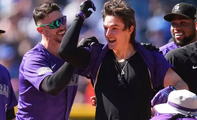 Colorado Rockies' Brenton Doyle, left, congratulates Mickey Moniak, second from left, after Moniak's walkoff RBI single off Chicago Cubs relief pitcher Daniel Palencia in the ninth inning of a baseball game Sunday, Aug. 31, 2025, in Denver. (AP Photo/David Zalubowski)