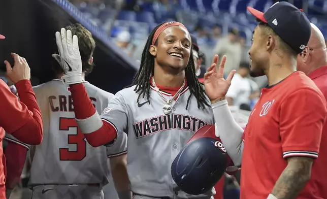 Washington Nationals' CJ Abrams, center, is congratulated in the dugout after scoring on a single hit by Josh Bell during the fifth inning of a baseball game against the Miami Marlins, Monday, Sept. 8, 2025, in Miami. (AP Photo/Lynne Sladky)