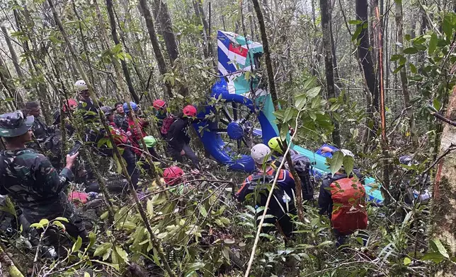 In this photo released by Indonesia's National Search and Rescue Agency (BASARNAS) on Thursday, Sept. 4, 2025, rescuers inspect the wreckage of a helicopter that crashed with passengers on board, in Tanah Bumbu, South Kalimantan, Indonesia. (BASARNAS via AP)