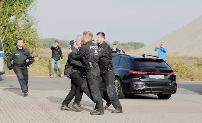Police officers push back a British photographer who tried to take pictures inside a car leaving a prison, carrying Christian B., a suspect in the 2007 disappearance of British toddler Madeleine McCann, in Sehnde, Germany, Wednesday, Sept. 17, 2025. (AP Photo/Markus Schreiber)