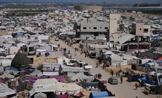 Displaced Palestinians walk through a tent camp in Muwasi, an area that Israel has designated as a safe zone, in Khan Younis southern Gaza Strip, Monday, Sept. 29, 2025. (AP Photo/Jehad Alshrafi)