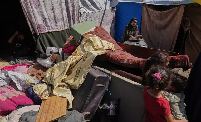 A woman stands beside her belongings after arriving from northern Gaza to a camp for displaced Palestinians in Muwasi, an area that Israel has designated as a safe zone, in Khan Younis southern Gaza Strip, Monday, Sept. 29, 2025. (AP Photo/Jehad Alshrafi).
