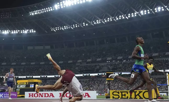 Qatar's Bassem Hemeida, left, falls during a men's 400 meters hurdles semifinal at the World Athletics Championships in Tokyo, Wednesday, Sept. 17, 2025. (AP Photo/Bernat Armangue)