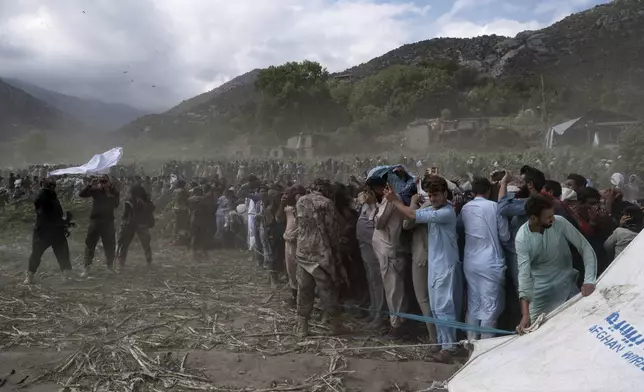 Residents and Taliban soldiers shield themselves from the wind of a helicopter taking off as efforts continue after Sunday night's powerful 6.0-magnitude earthquake that struck several provinces, in Kunar province, eastern Afghanistan, Tuesday, Sept. 2, 2025. (AP Photo/Nava Jamshidi)