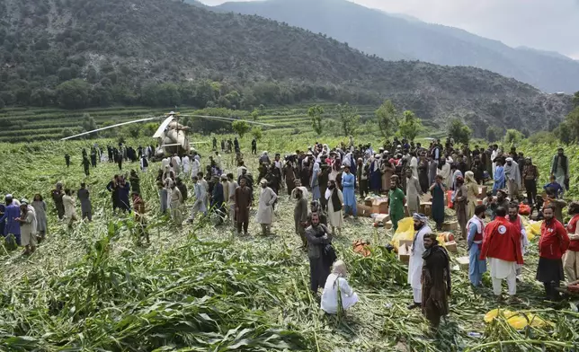 Local residents gather around a military helicopter that landed to evacuate injured victims of an earthquake that killed many people and destroyed villages in eastern Afghanistan, in Mazar Dara, Kunar province, Afghanistan, Monday, Sept. 1, 2025. (AP Photo/Wahidullah Kakar)