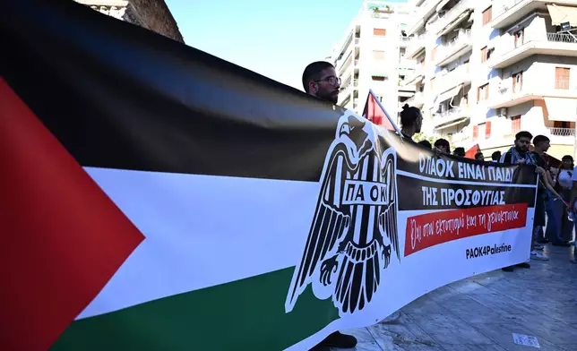 Pro-Palestinian protesters, most of them PAOK fans, hold a banner that reads "PAOK is the child of refugees. No to displacement and genocide" as they gather ahead of a Europa League soccer match between PAOK and Israeli team Maccabi Tel Aviv in the port city of Thessaloniki, northern Greece, Wednesday, Sept. 24, 2025. (AP Photo/Giannis Papanikos)