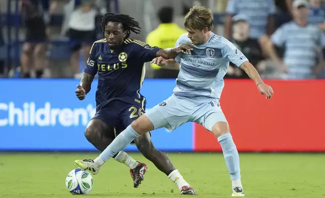 Sporting Kansas City midfielder Jake Davis, right, kicks the ball under pressure from Vancouver Whitecaps midfielder Jean-Claude Ngando (26) during the second half of an MLS soccer match Saturday, Sept. 20, 2025, in Kansas City, Kan. (AP Photo/Charlie Riedel)