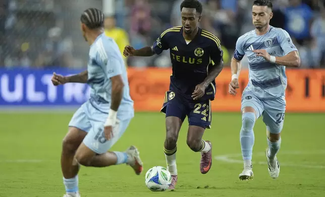 Vancouver Whitecaps midfielder Ali Ahmed (22) is chased by Sporting Kansas City midfielder Erik Thommy, right, during the second half of an MLS soccer match Saturday, Sept. 20, 2025, in Kansas City, Kan. (AP Photo/Charlie Riedel)