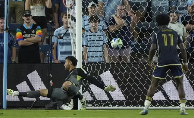 A ball kicked by Vancouver Whitecaps midfielder Kenji Cabrera gets past Sporting Kansas City goalkeeper John Pulskamp, left, to score a goal during the first half of an MLS soccer match Saturday, Sept. 20, 2025, in Kansas City, Kan. (AP Photo/Charlie Riedel)