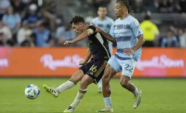 Vancouver Whitecaps midfielder Sebastian Berhalter (16) kicks the ball away from Sporting Kansas City midfielder Zorhan Bassong (22) during the second half of an MLS soccer match Saturday, Sept. 20, 2025, in Kansas City, Kan. (AP Photo/Charlie Riedel)