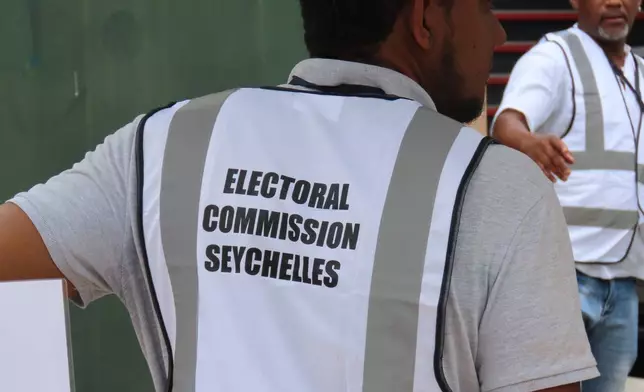 An electoral commission staff member directs voters toward the polling station at English River School in Victoria, Seychelles, Thursday, Sept. 25, 2025. (AP Photo/Emilie Chetty)