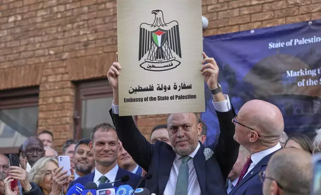 Husam S. Zomlot, Ambassador for the Palestinian Mission to the United Kingdom holds up a new sign during a Palestinian flag raising ceremony at the Palestinian Mission in London, Monday, Sept. 22, 2025.(AP Photo/Frank Augstein)