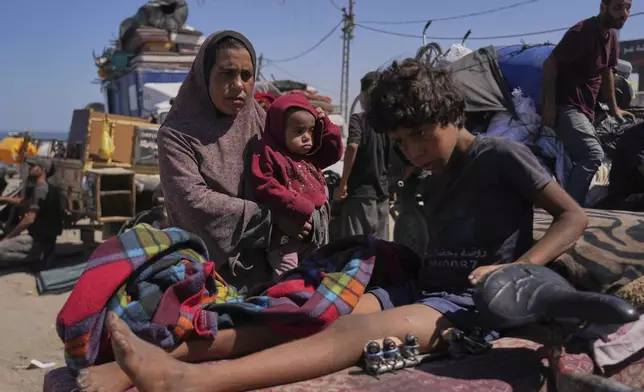 Amal Al-Qishawi, follows her injured son, Yasser, 11, carried on a bicycle by his father Rafiq Al-Qishawi, as they flee northern Gaza Strip walking along the coastal road, near Wadi Gaza, Saturday, Sept. 20, 2025. (AP Photo/Abdel Kareem Hana)