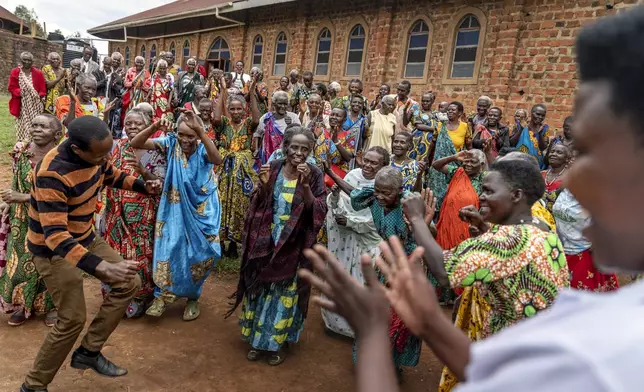 Gift Amumpeire, left, a field assistant with Reach One Touch One Ministries, dances with members of the elderly community at their biweekly fellowship gathering at a church, Wednesday, Nov. 20, 2024, in Rwamucucu, Western Region of Uganda. (AP Photo/David Goldman)