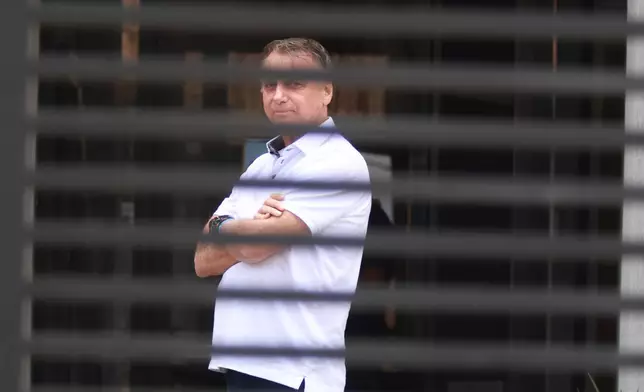 Brazil's former President Jair Bolsonaro stands at the entrance of his home where he is under house arrest in Brasilia, Brazil, Tuesday, Sept. 2, 2025. (AP Photo/Luis Nova)