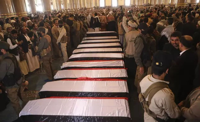 People gather as officers stand guard beside the coffins of Houthi officials, including Prime Minister Ahmed al-Rahawi, who were killed in Israeli airstrikes on Thursday, during their funeral inside the Shaab Mosque in Sanaa, Yemen, Monday, Sept. 1, 2025. (AP Photo/Osamah Abdulrahman)