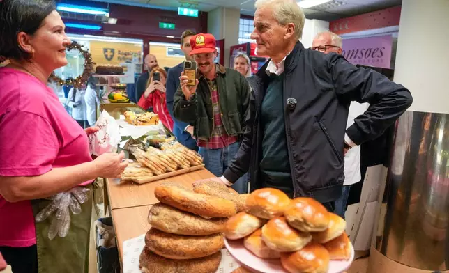 Jonas Gahr Store, right, chairman of Norway's Ap party buys food during an election tour in Stavanger, Norway, Wednesday, Sept. 3, 2025. (Stian Lysberg Solum/NTB Scanpix via AP)