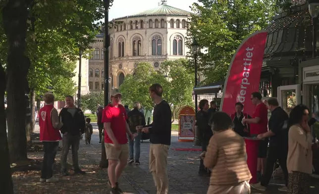 Campaign volunteers from the Labour Party, wearing red, engage with people near the Norwegian Parliament building in Oslo, Sunday, Sept. 7, 2025. (AP Photo/Kostya Manenkov)