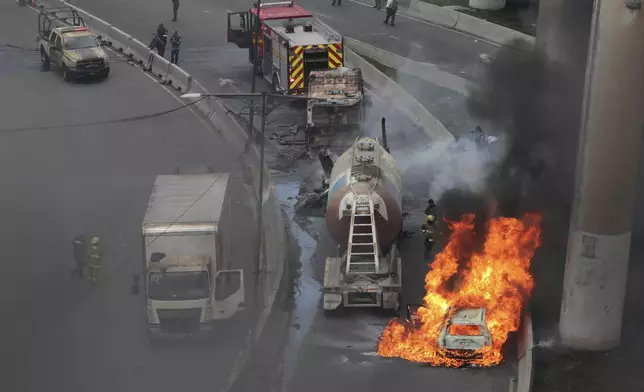 A vehicle burns near the site of a gas tanker explosion under a highway overpass in Mexico City, Wednesday, Sept. 10, 2025. (AP Photo/Tristan Velazquez)