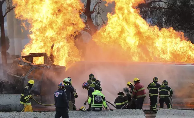 Firefighters spray hoses at a gas tanker that exploded under a highway overpass in Mexico City, Wednesday, Sept. 10, 2025. (AP Photo/Tristan Velazquez)