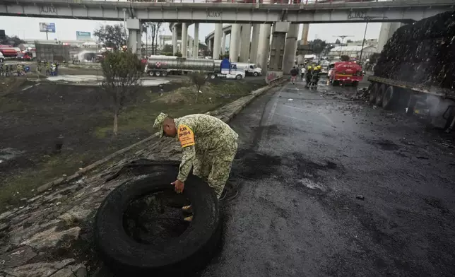 A soldier removes a burned tire from the scene of a gas tanker explosion in Mexico City, Wednesday, Sept. 10, 2025. (AP Photo/Fernando Llano)