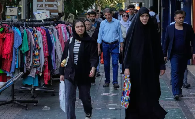 People walk on a sidewalk at the Enqelab-e-Eslami (Islamic Revolution) street, in Tehran, Iran, Saturday, Sept. 27, 2025. (AP Photo/Vahid Salemi)