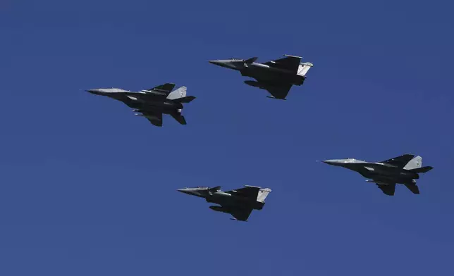 Serbian army MiG-29 jets, left and right, and French Air Force Rafale fighter jets fly in the sky during a military parade in Belgrade, Serbia, Saturday, Sept. 20, 2025. (AP Photo/Darko Vojinovic)