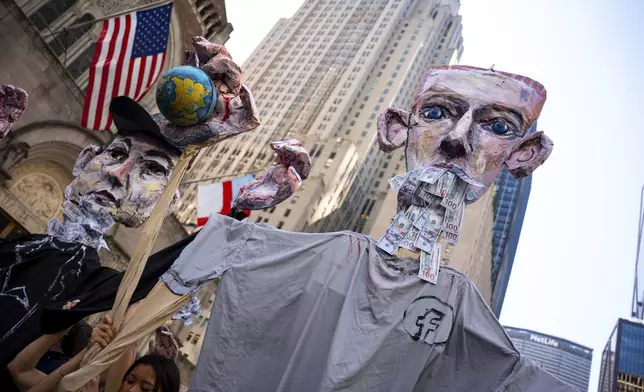 Art pieces of Mark Zuckerberg and Elon Musk with bloody hands carrying globes are marched through Manhattan at the "Make Billionaires Pay" climate protest, Saturday, Sept. 20, 2025, in New York. (AP Photo/Angelina Katsanis)