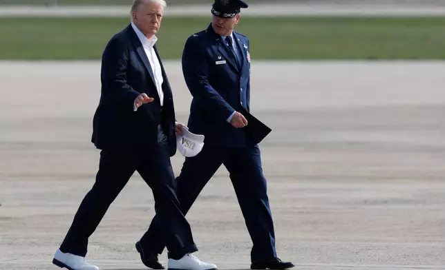 President Donald Trump waves as he is escorted by Air Force Col. Christopher M. Robinson, Commander, 89th Airlift Wing, before boarding Air Force One, Friday, Sept. 26, 2025, at Joint Base Andrews, Md., en route to the Ryder Cup golf tournament at Bethpage Black in Farmingdale, N.Y.(AP Photo/Luis M. Alvarez)