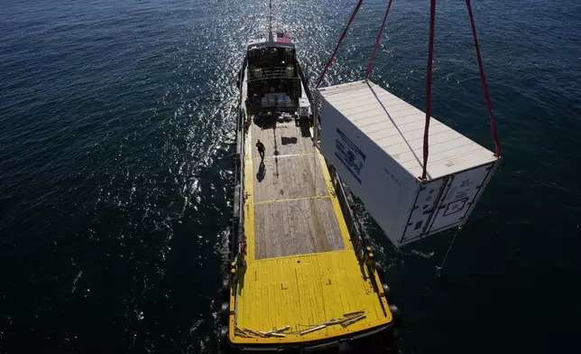 A supply container is lifted from the Gaspee, a crew transport vessel, to the Liftboat Robert platform during an Expedition 501 crew and supply transfer in the North Atlantic, Saturday, July 19, 2025. (AP Photo/Carolyn Kaster)