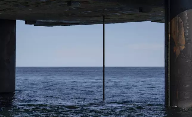 The wireline drilling core barrel is visible from the underside of the Liftboat Robert platform, from the Gaspee, a crew transport vessel, in the North Atlantic, Saturday, July 19, 2025. (AP Photo/Carolyn Kaster)