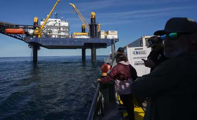 Expedition 501 members look down from the Liftboat Robert platform, to the approaching Gaspee, a crew transport vessel, in the North Atlantic, Saturday, July 19, 2025. (AP Photo/Carolyn Kaster)