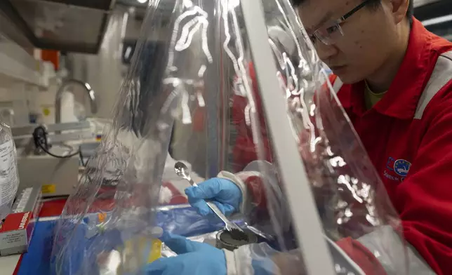 Expedition 501 researchers Xinxu Zhang, of Shenzhen University China, works in a container to ensure a sterile environment aboard the Liftboat Robert platform, in the North Atlantic, Sunday, July 20, 2025. (AP Photo/Carolyn Kaster)