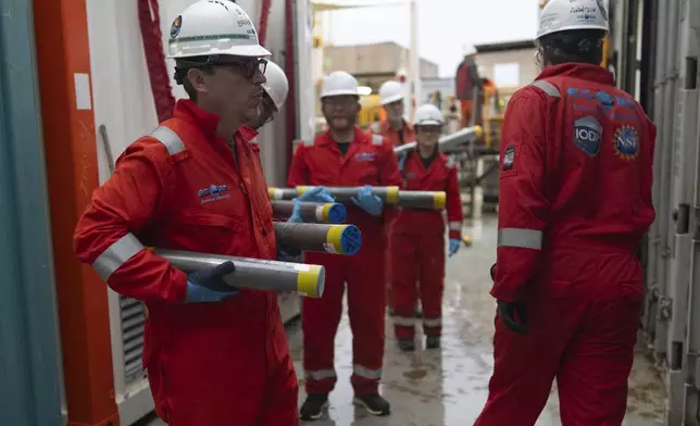 Expedition 501 researchers, including Brandon Dugan, Expedition 501 co-chief scientist, carry cores to a cold storage container aboard the Liftboat Robert platform, in the North Atlantic, Sunday, July 20, 2025. (AP Photo/Carolyn Kaster)