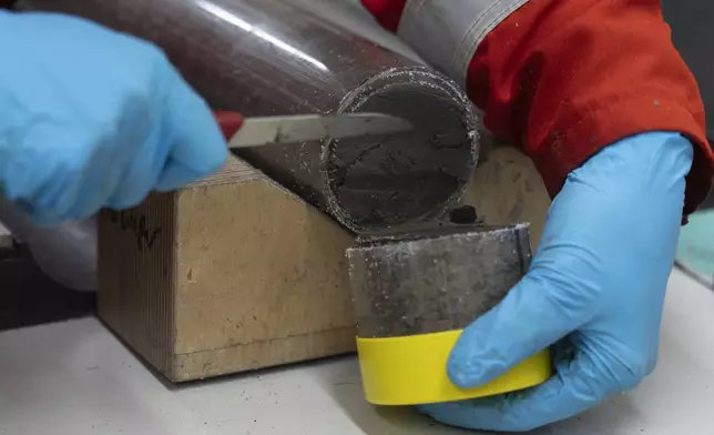 Patrizia Geprags, Expedition 501 researcher, cuts a whole round sample that will be squeezed in the curation container aboard the Liftboat Robert platform in the North Atlantic, in the early morning hours of Sunday, July 20, 2025. (AP Photo/Carolyn Kaster)