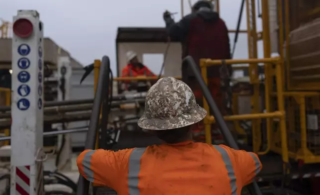 Grease-covered Expedition 501 drilling team member Chris Redding works on the wireline core drilling rig aboard the Liftboat Robert platform, in the North Atlantic, Sunday, July 20, 2025. (AP Photo/Carolyn Kaster)
