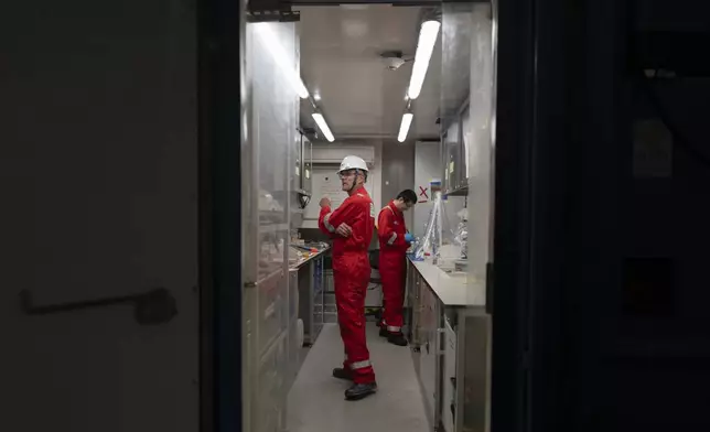 Expedition 501 researchers Xinxu Zhang, of Shenzhen University China, right, and Antonio Ferreira, an environmental geochemist with the British Geological Survey, work aboard the Liftboat Robert platform, in the North Atlantic, Sunday, July 20, 2025. (AP Photo/Carolyn Kaster)