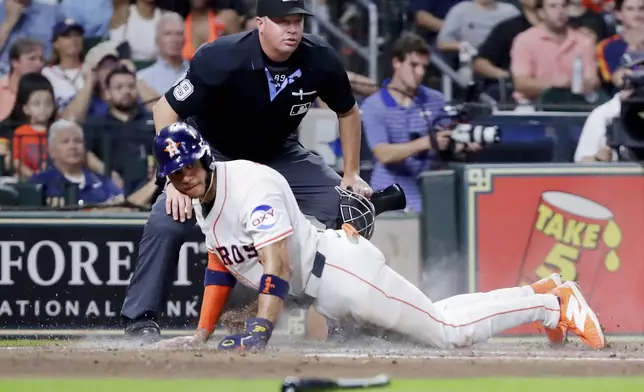 Houston Astros' Jeremy Pena scores his second run in front of umpire Cory Blaser, top, against the Texas Rangers during the third inning of a baseball game Tuesday, Sept. 16, 2025, in Houston. (AP Photo/Michael Wyke)
